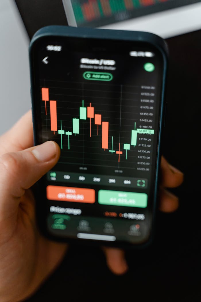 Hand holding smartphone displaying cryptocurrency trading graph in app.